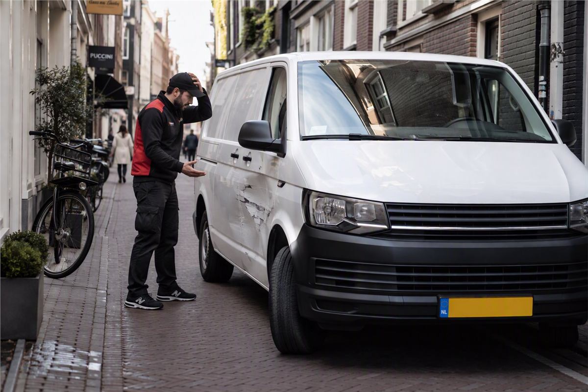 Koerier bekijkt een deuk in zijn bestelbus